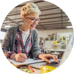 A woman working on a laptop in a workshop.