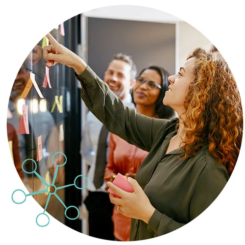 Team members collaborate over sticky notes on a wall, showcasing team-building in an innovation workshop.