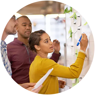 Two men and a women working on a marketing challenge by brainstorming on a wall.