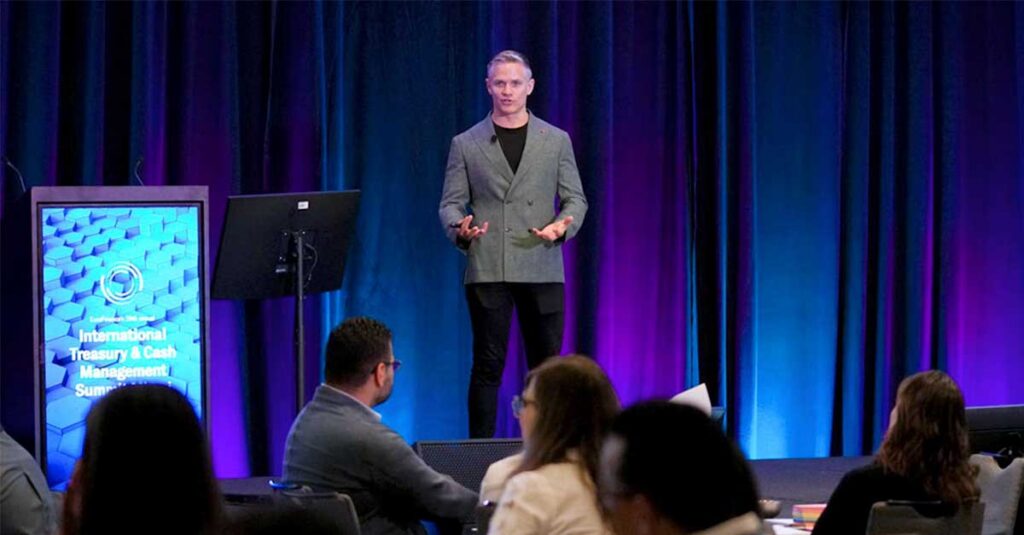 Man stands on stage talking about how to adopt AI meaningfully at a EuroFinance Global Summit.